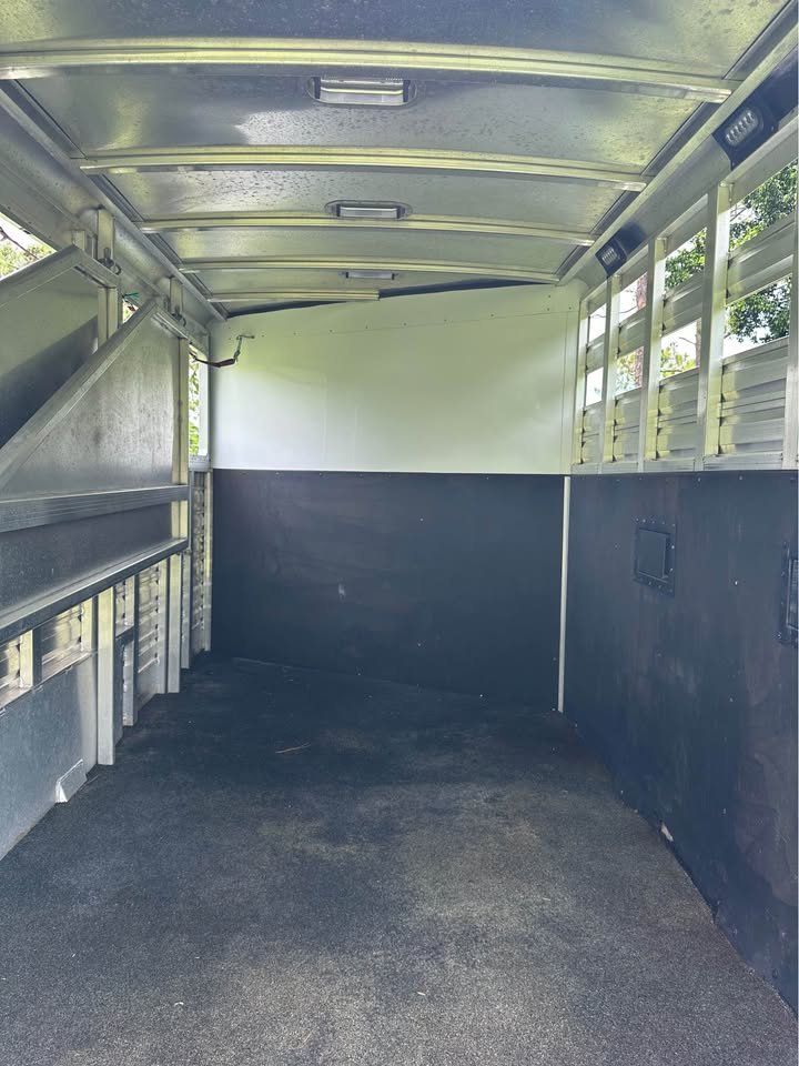 A folding rear tack room with an adjustable three-tier saddle rack and bridle hooks."