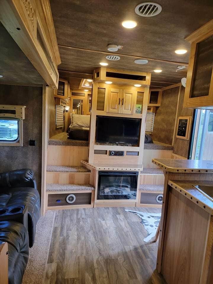 A spacious rear tack room featuring adjustable saddle tiers and multiple bridle hooks